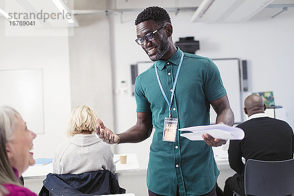 Lächelnder männlicher Community-College-Lehrer im Gespräch mit einem Studenten im Klassenzimmer