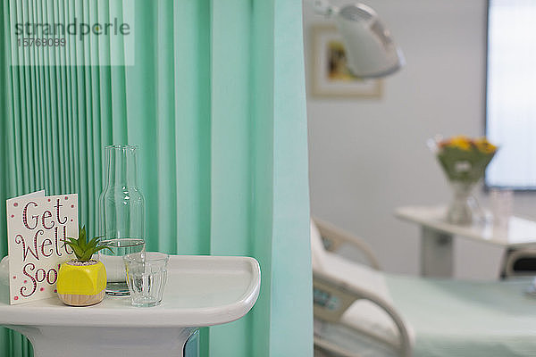 Gute Besserung-Karte und Wasserkaraffe auf einem Tablett in einem leeren Krankenhauszimmer