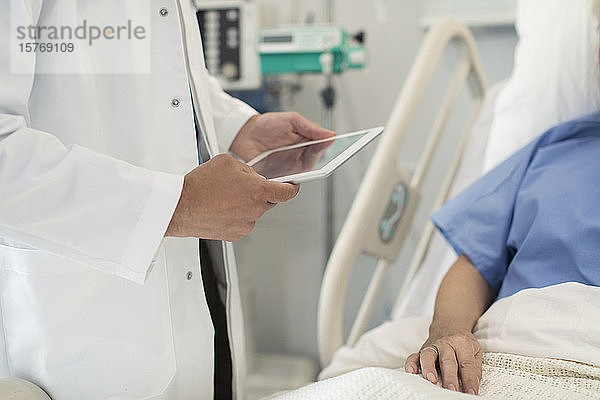 Arzt mit digitalem Tablet bei der Visite  Überprüfung eines Patienten im Krankenhausbett