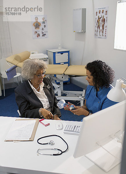 Eine Ärztin unterrichtet einen älteren Patienten in der Verwendung eines Inhalators in einer Arztpraxis