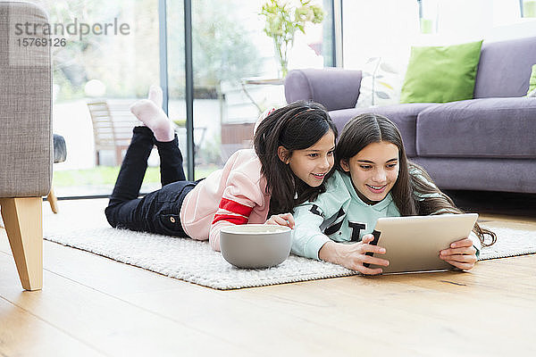 Mädchen schauen Film mit digitalem Tablet auf dem Wohnzimmerboden