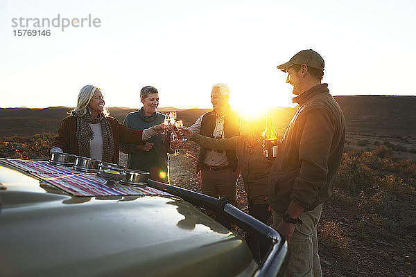 Safari-Gruppe stößt bei Sonnenuntergang mit Champagnergläsern an