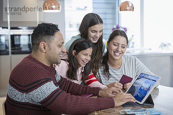 Glückliche Familie bei der Urlaubsplanung am digitalen Tablet in der Küche