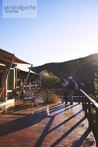 Zärtliches älteres Paar  das sich auf dem sonnigen Balkon einer Safari-Lodge umarmt