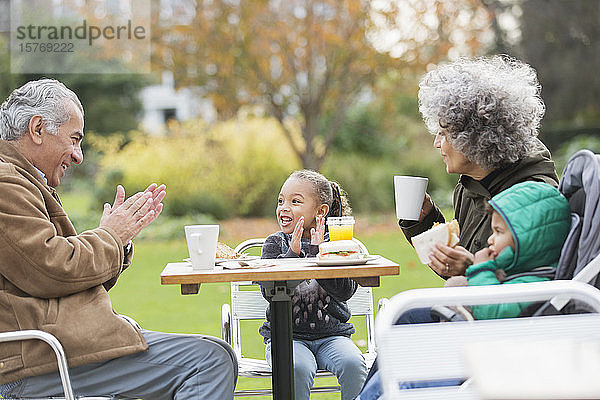 Großeltern und Enkelkinder genießen das Mittagessen am Tisch im Park