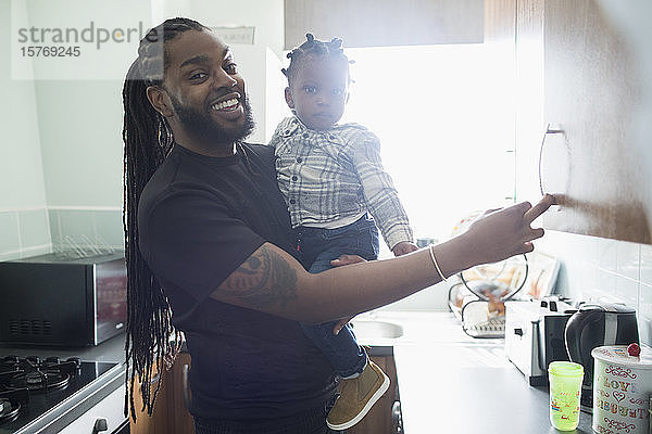 Porträt eines glücklichen Vaters  der sein Kleinkind in der Küche einer Wohnung hält