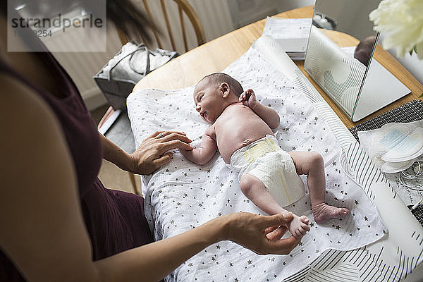 Mutter wechselt die Windel ihres neugeborenen Sohnes auf dem Wickeltisch