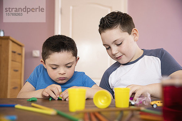 Junge mit Down-Syndrom und Bruder spielen mit Spielzeug