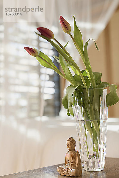 Tulpenstrauß in Vase und hölzerne Buddha-Statuette