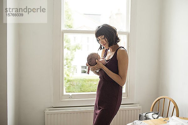 Mutter hält neugeborenen Sohn am Fenster