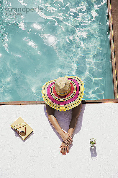 Frau mit Sonnenhut entspannt sich im Schwimmbad