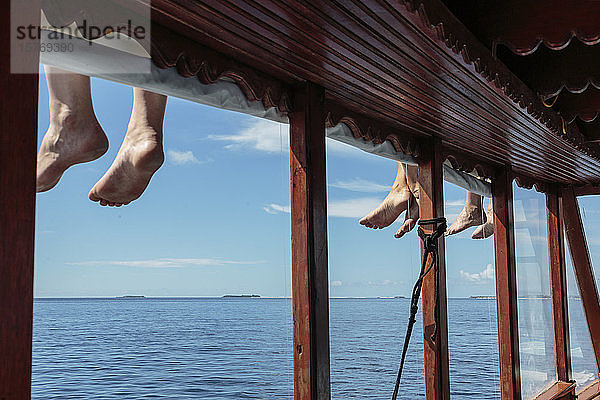 Nackte Füße baumeln über dem sonnigen Ozeandock  Malediven