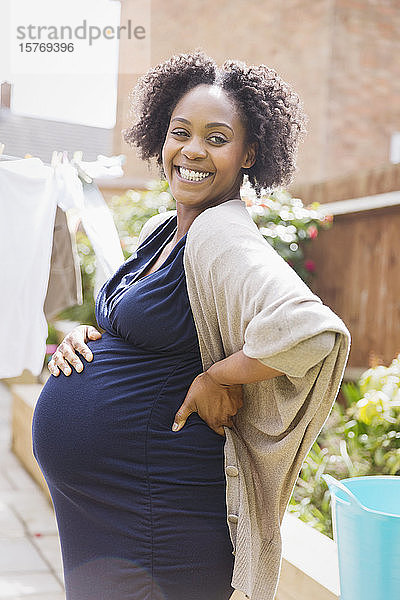 Porträt glückliche schwangere Frau im sonnigen Garten