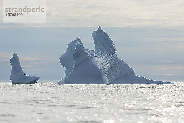 Majestätische Eisbergformationen auf dem sonnigen Atlantischen Ozean Grönlands