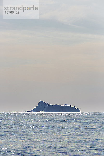 Eisberg in der Ferne auf dem sonnigen  ruhigen Atlantischen Ozean Grönlands