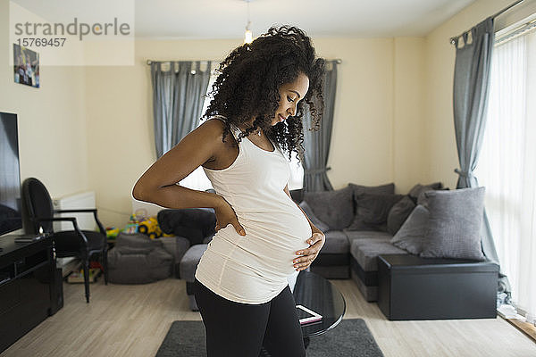 Schöne junge schwangere Frau hält Bauch