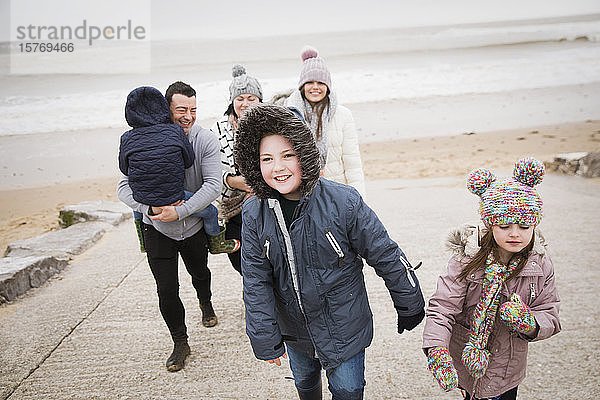 Glückliche Familie in warmer Kleidung geht die Strandrampe hinauf