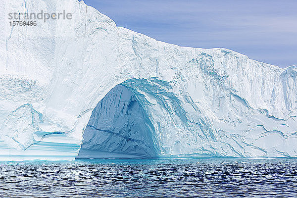 Majestätischer Eisbergbogen über dem sonnigen blauen Ozean Grönlands