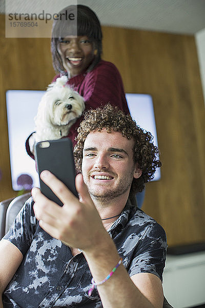 Glückliches junges Paar mit Hund im Videochat mit Smartphone