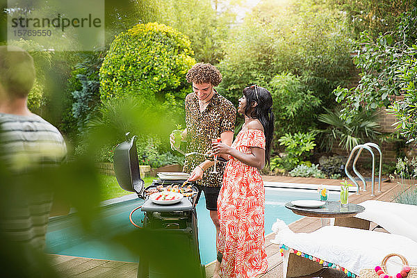 Junges multiethnisches Paar beim Grillen am Sommerpool