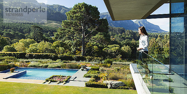 Frau auf sonnigem  luxuriösem Balkon mit Blick auf Swimmingpool und Landschaft  Kapstadt  Südafrika