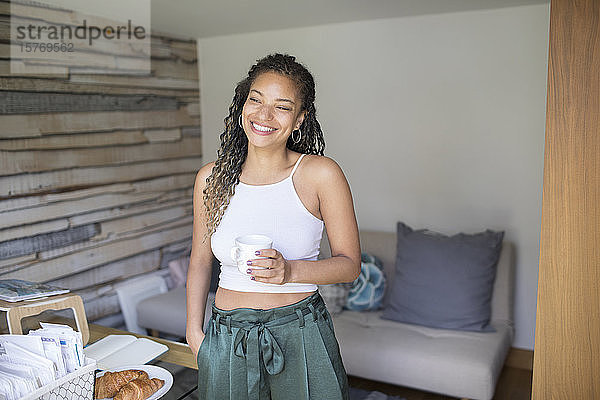 Porträt glückliche junge Frau trinkt Kaffee im Heimbüro