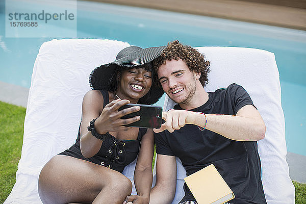 Glückliches junges Paar nimmt Selfie mit Kamera-Handy am Pool