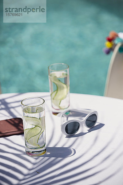 Gurkenwasser und Sonnenbrille auf dem sonnigen Terrassentisch am Pool