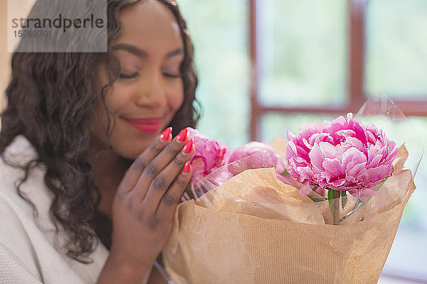 Junge Frau riecht an frischer rosa Pfingstrose Blumenstrauß