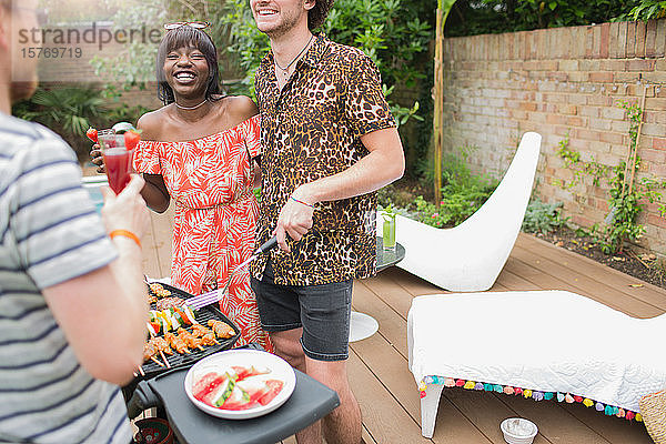 Glückliches junges multiethnisches Paar beim Grillen auf der Sommerterrasse