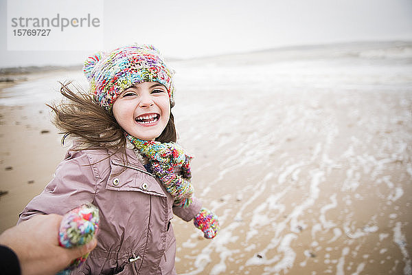 Porträt glückliches sorgloses Mädchen läuft am Winterstrand
