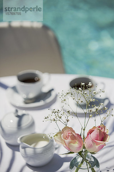 Rosen und Kaffee auf dem sonnigen Terrassentisch