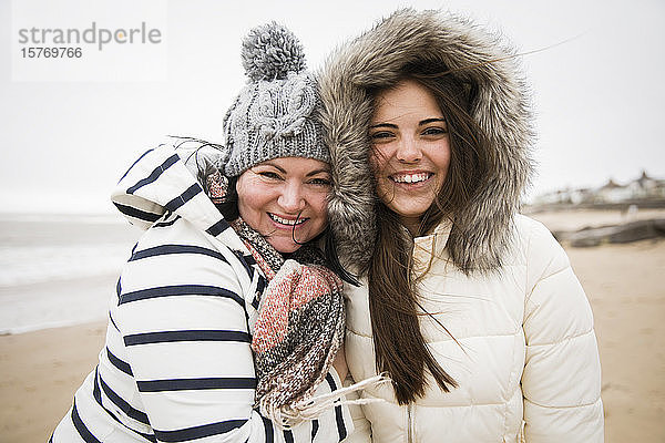 Portrait glückliche Mutter und Tochter in warmer Kleidung am Strand