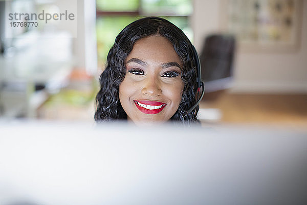 Portrait lächelnde junge Frau mit Headset bei der Arbeit am Computer