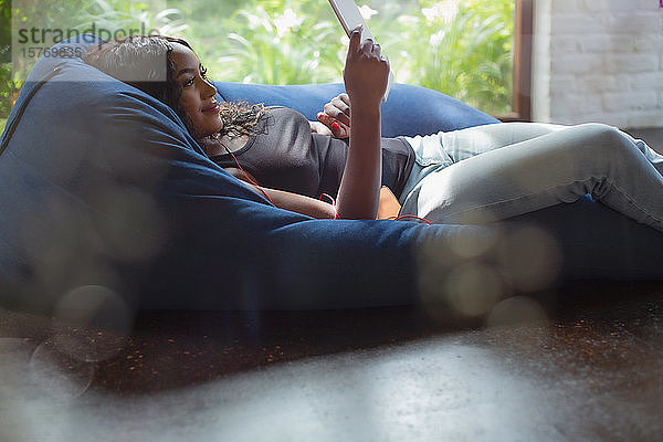 Junge Frau entspannt sich mit digitalem Tablet im Sitzsack