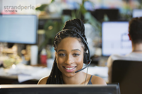 Porträt einer selbstbewussten Geschäftsfrau mit Headset am Computer im Büro