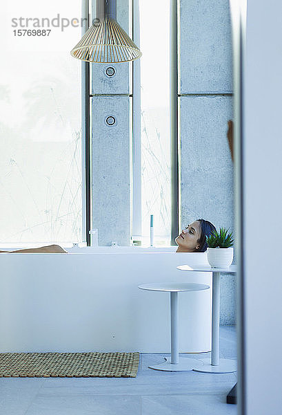 Gelassene Frau entspannt sich in einer Badewanne in einem modernen Badezimmer