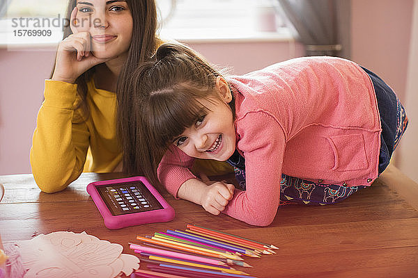Porträt glückliche Schwestern mit digitalem Tablet auf dem Tisch