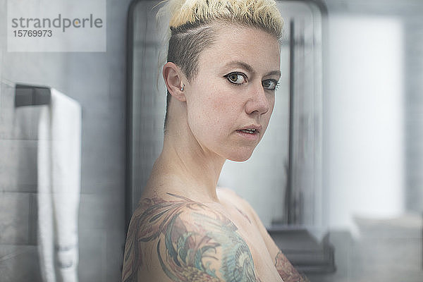 Porträt selbstbewusste Frau mit Tattoos und nackten Schultern im Badezimmer