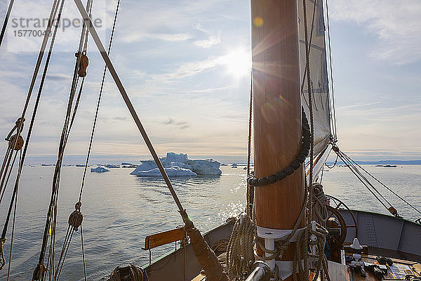 Schiff fährt auf Eisberge zu auf dem sonnigen  ruhigen Atlantik in Grönland