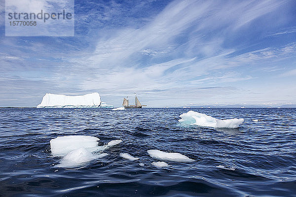 Segelboot zwischen schmelzendem Polareis auf dem sonnigen Atlantik in Grönland