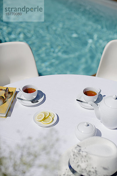 Teeservice auf dem sonnigen Terrassentisch im Sommer am Pool