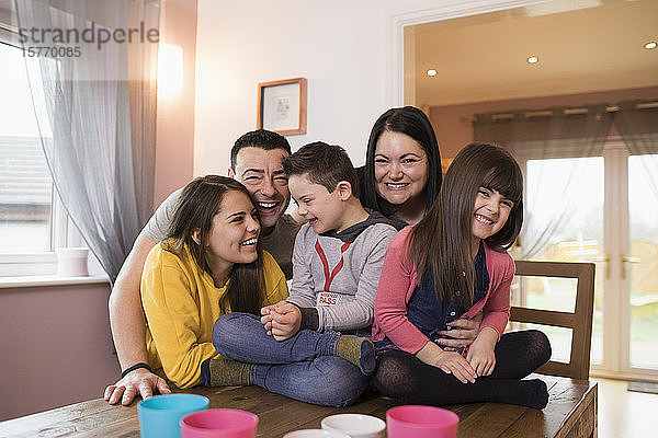 Porträt einer glücklichen Familie mit Down-Syndrom-Kind am Esstisch