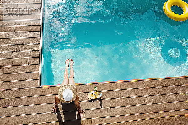 Frau mit Sonnenhut entspannt sich  nimmt ein Sonnenbad am sonnigen Sommerpool