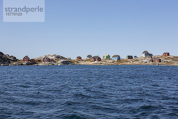 Bunte Häuser an der sonnigen  abgelegenen Küste der Diskobucht in Westgrönland