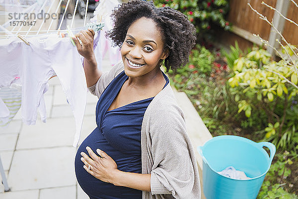 Porträt glückliche schwangere Frau hängt Wäsche auf Wäscheleine