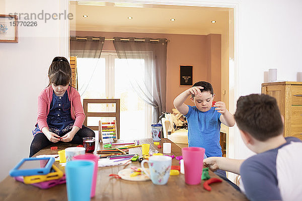 Brüder und Schwester spielen mit Spielzeug am Esstisch