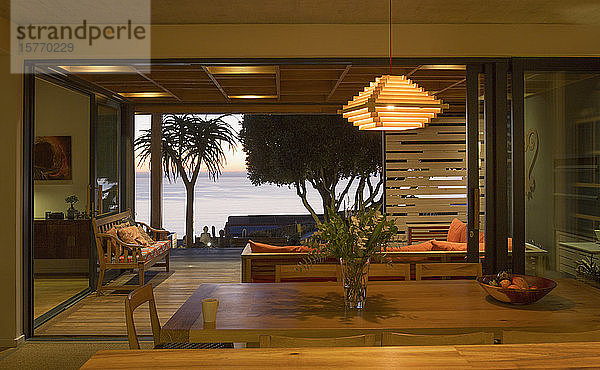 Beleuchtetes  modernes  luxuriöses Wohnhaus mit offenem Esszimmer zur Terrasse mit Meerblick