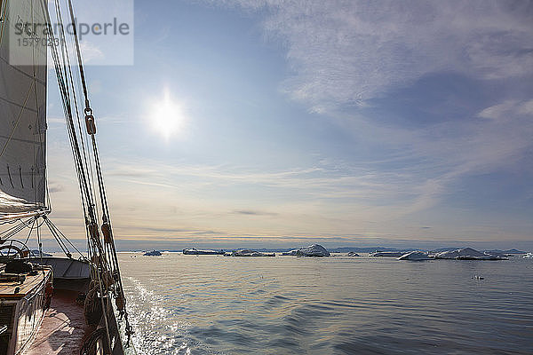 Schiff fährt auf schmelzendes Eis zu  auf dem sonnigen  ruhigen Atlantik in Grönland