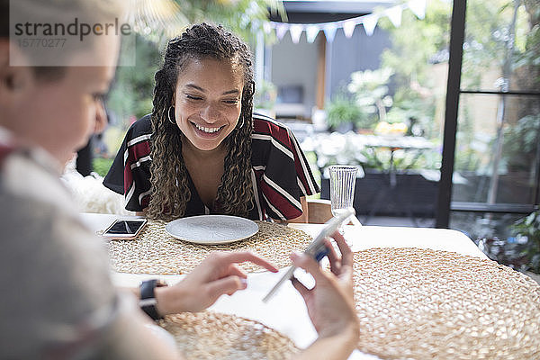 Junge Freundinnen benutzen ein Smartphone am Esstisch